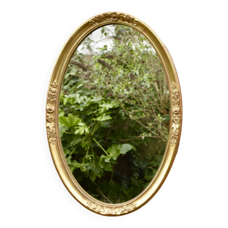 Old large oval wall mirror in golden resin