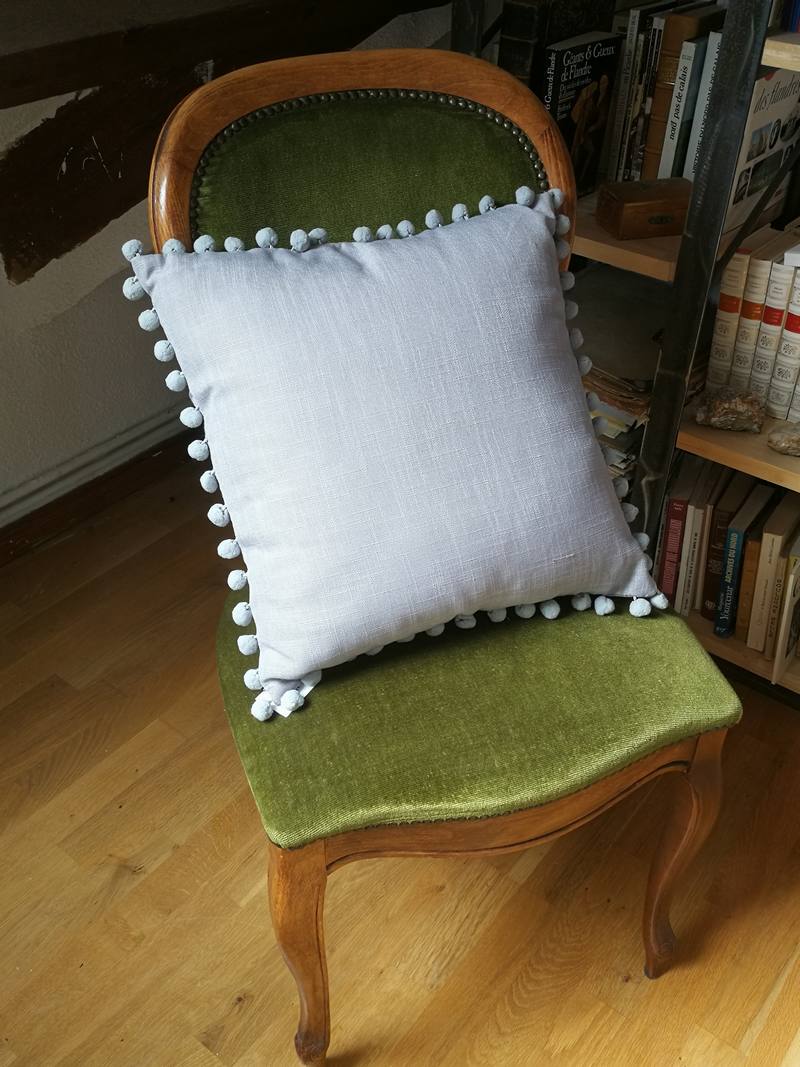 Gray cushion with pompoms
