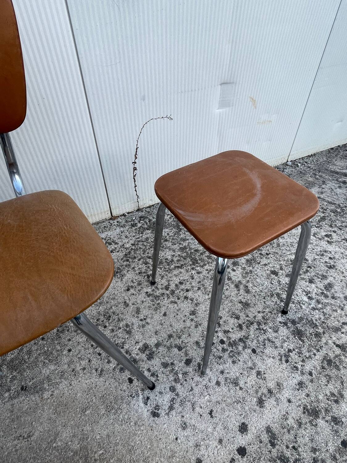 3 chairs and a vintage stool in faux leather and tubular design.