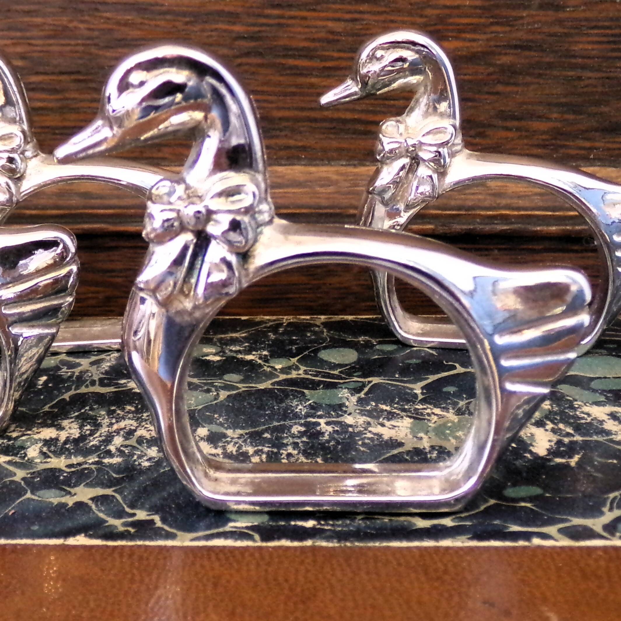Four silver-plated napkin rings in the shape of a duck/goose