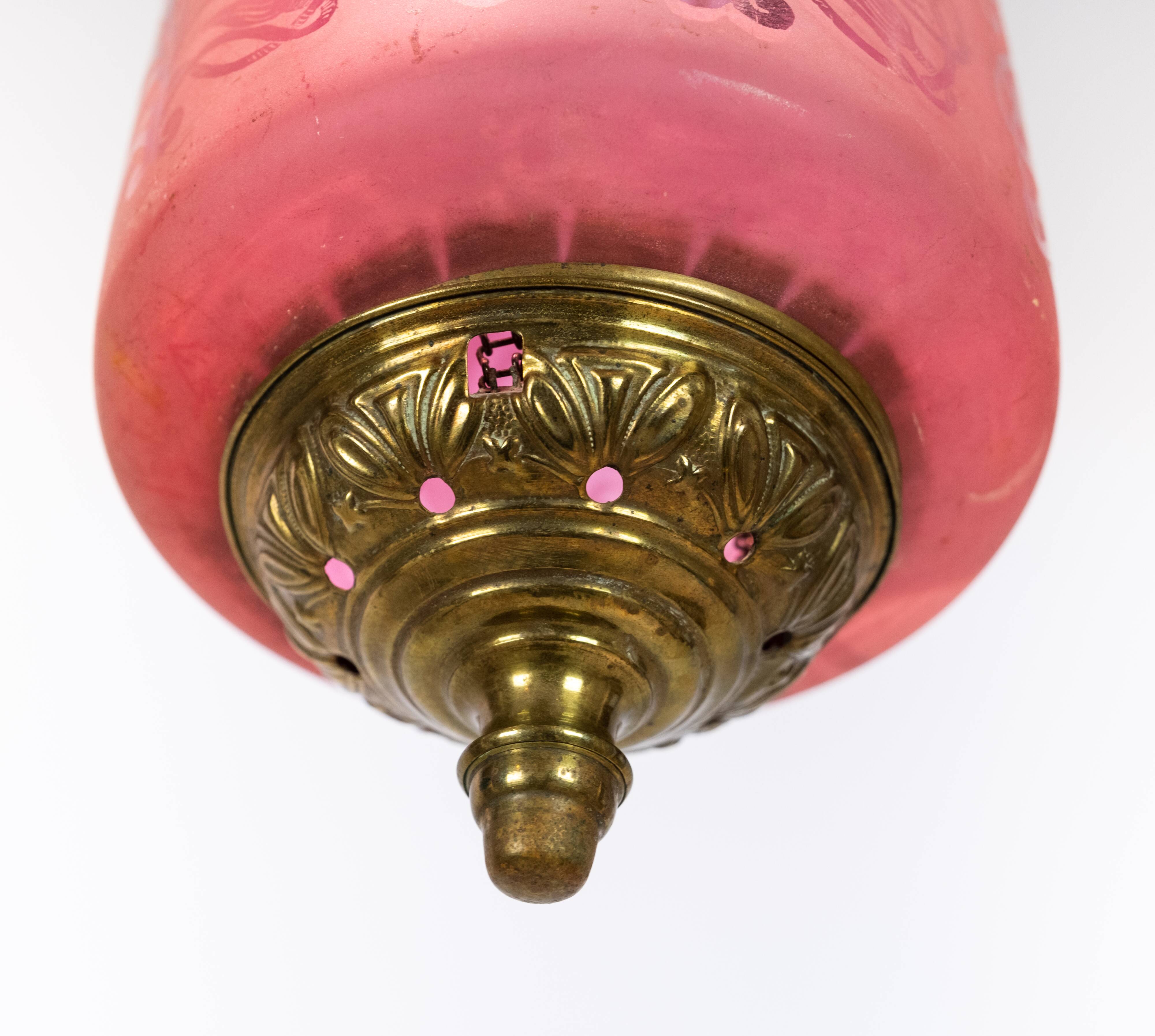 Antique pendant of pink opaline glass with brass edge and suspension from around 1860