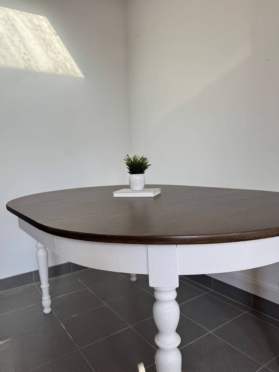 Restored solid wood round table with integrated extensions.