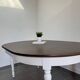 Restored solid wood round table with integrated extensions.