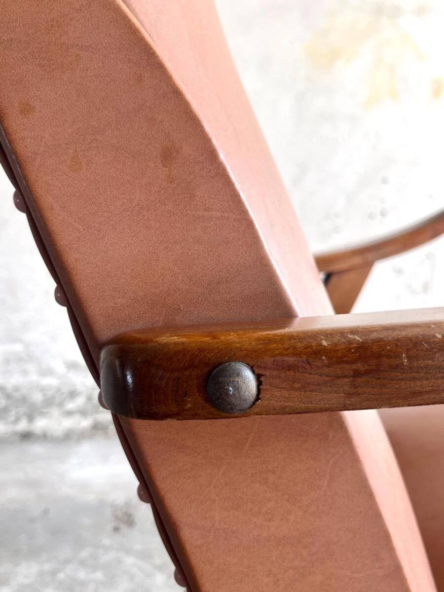 Vintage armchair from the 1950s in cognac leather and dark wood — modernist lounge chair.