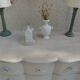 A beautifully crafted crossbow-shaped chest of drawers, finished in pearl grey with a whitewashed top.