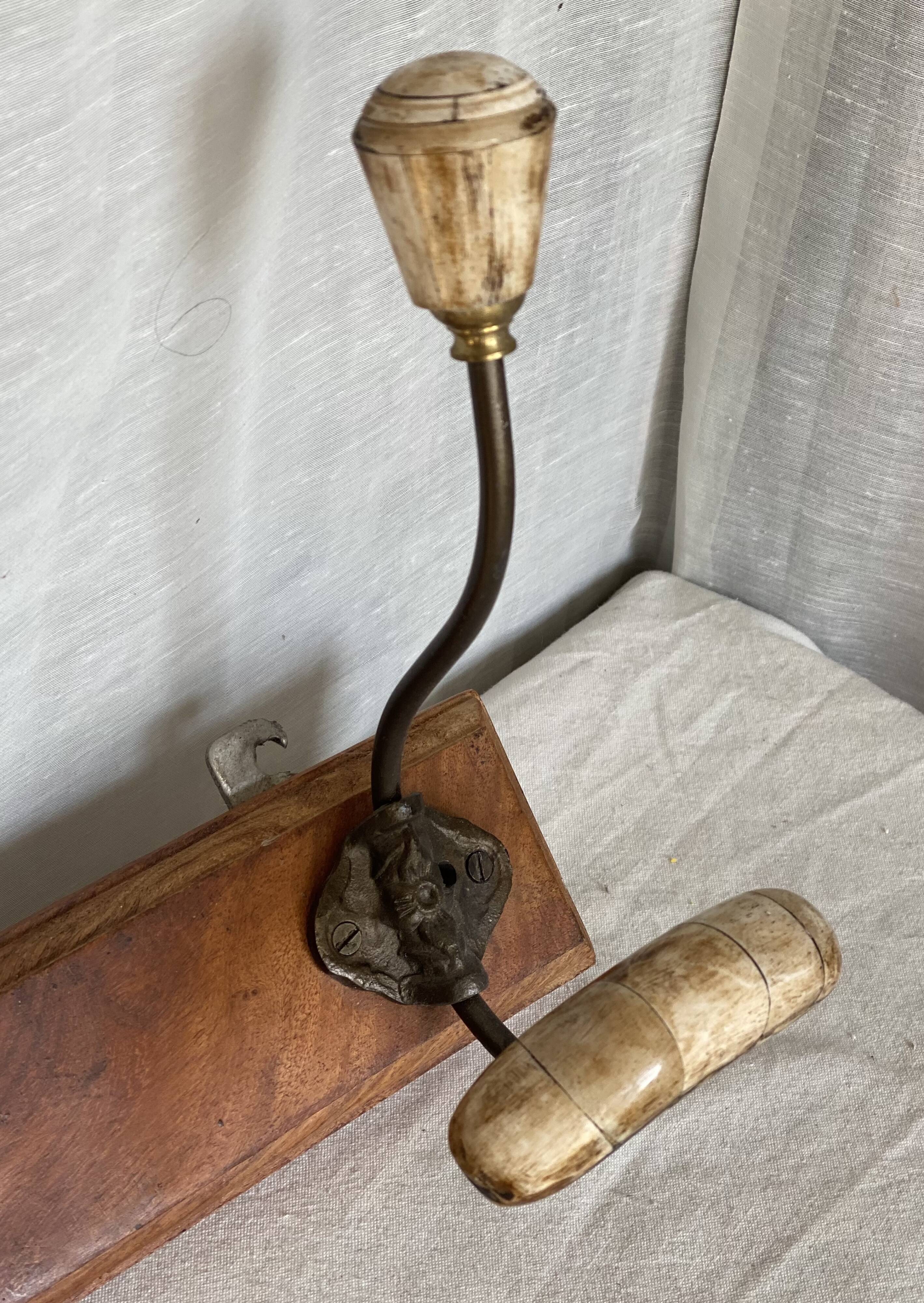 19th-century wall coat rack with 2 metal and horn hooks.
