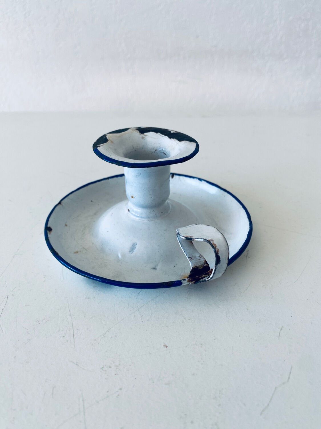 Old candle holder in white enameled metal