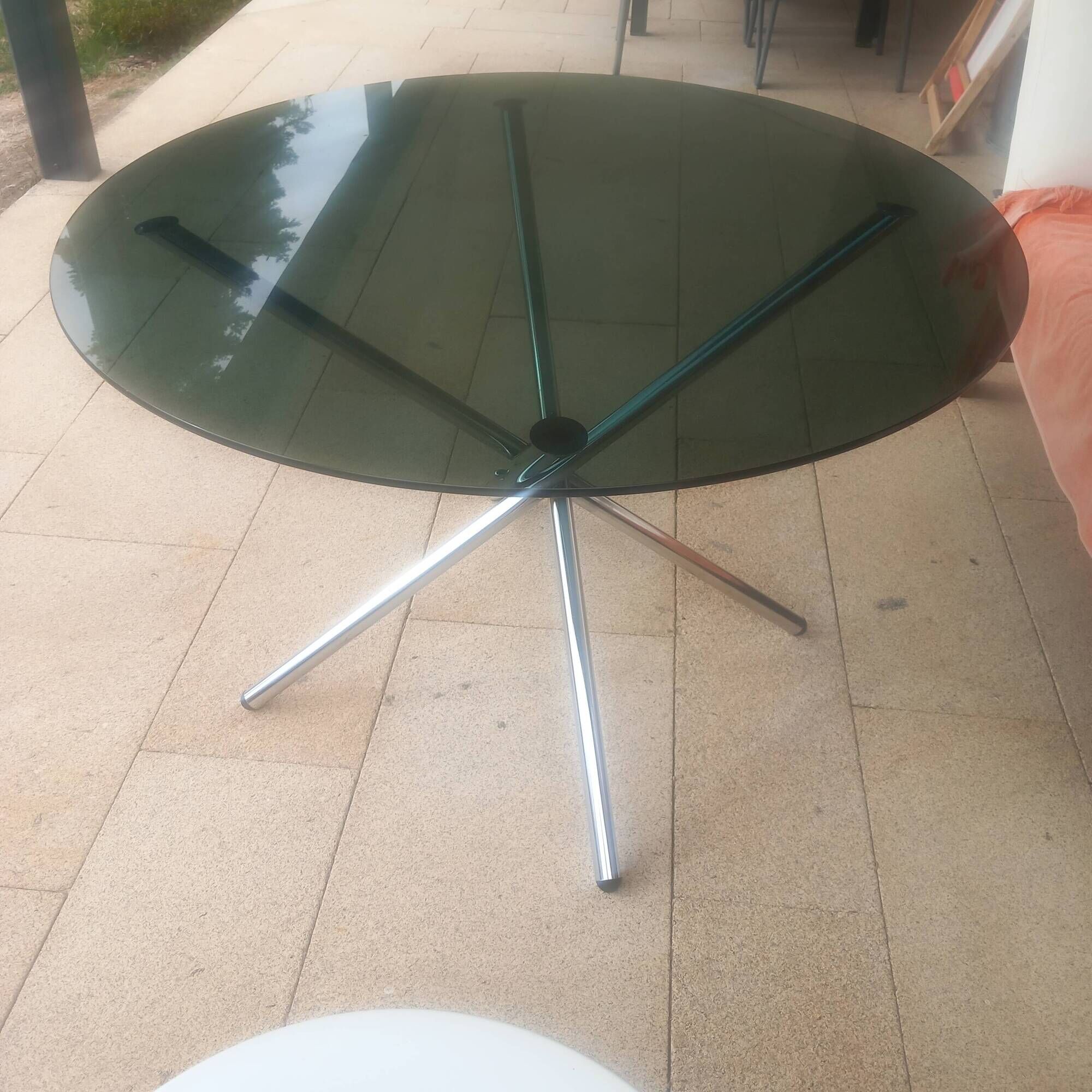 Round smoked glass table from the 70s. Foldable stainless steel legs.