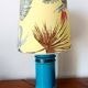 Blue ceramic lamp with claw feet and foliage lampshade.