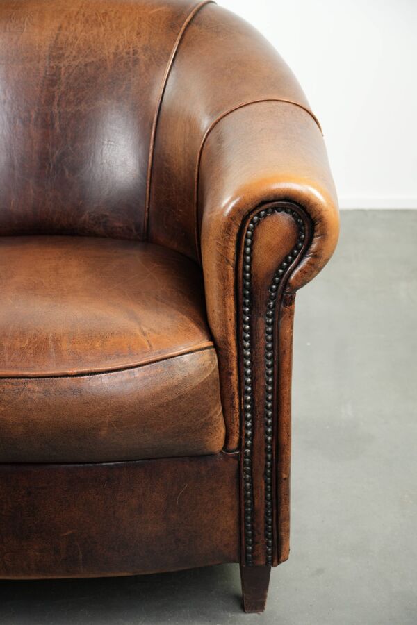 Fauteuil club en cuir de peau de mouton avec un coussin de siège fixe.