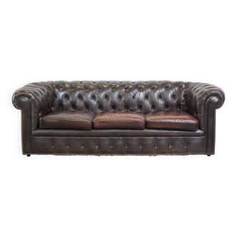Old dark brown 3-seater cowhide chesterfield sofa with lots of character