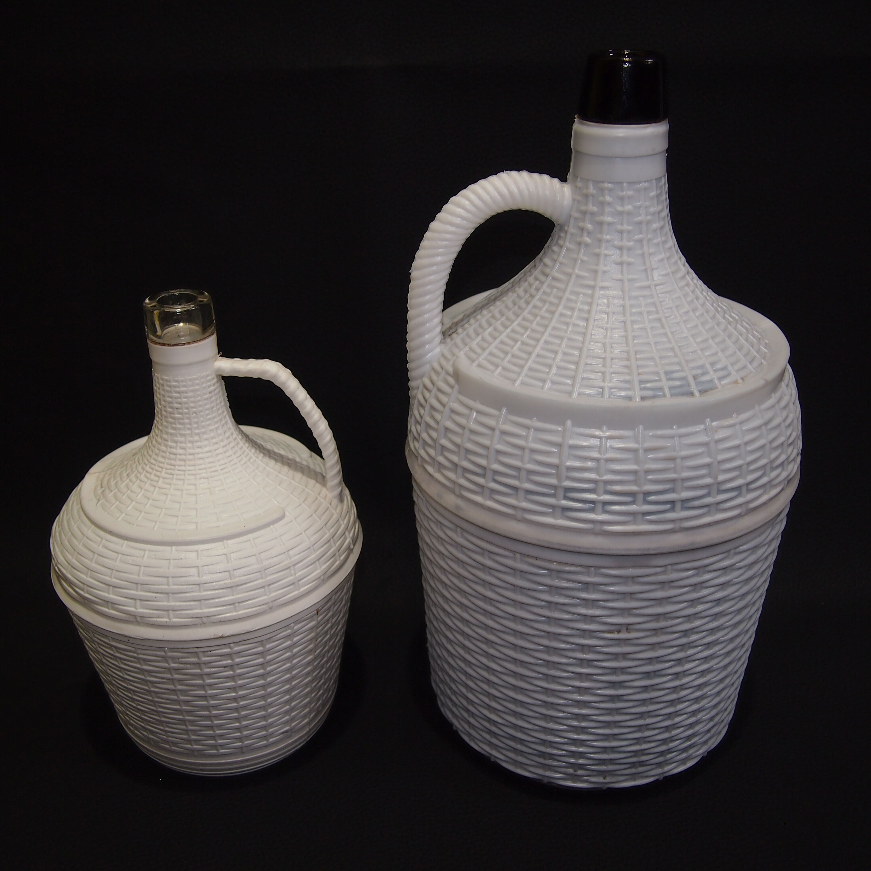 Pair of white covered demijohns
