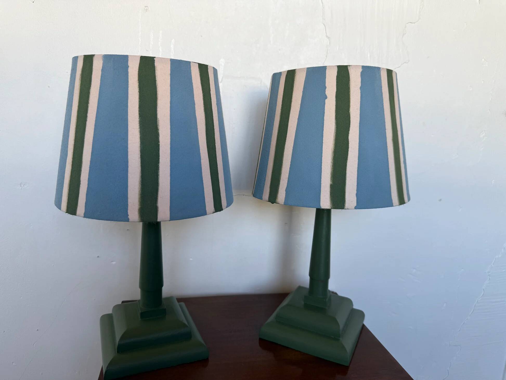 Pair of vintage wooden lamps with their striped beige, blue, and green shades.