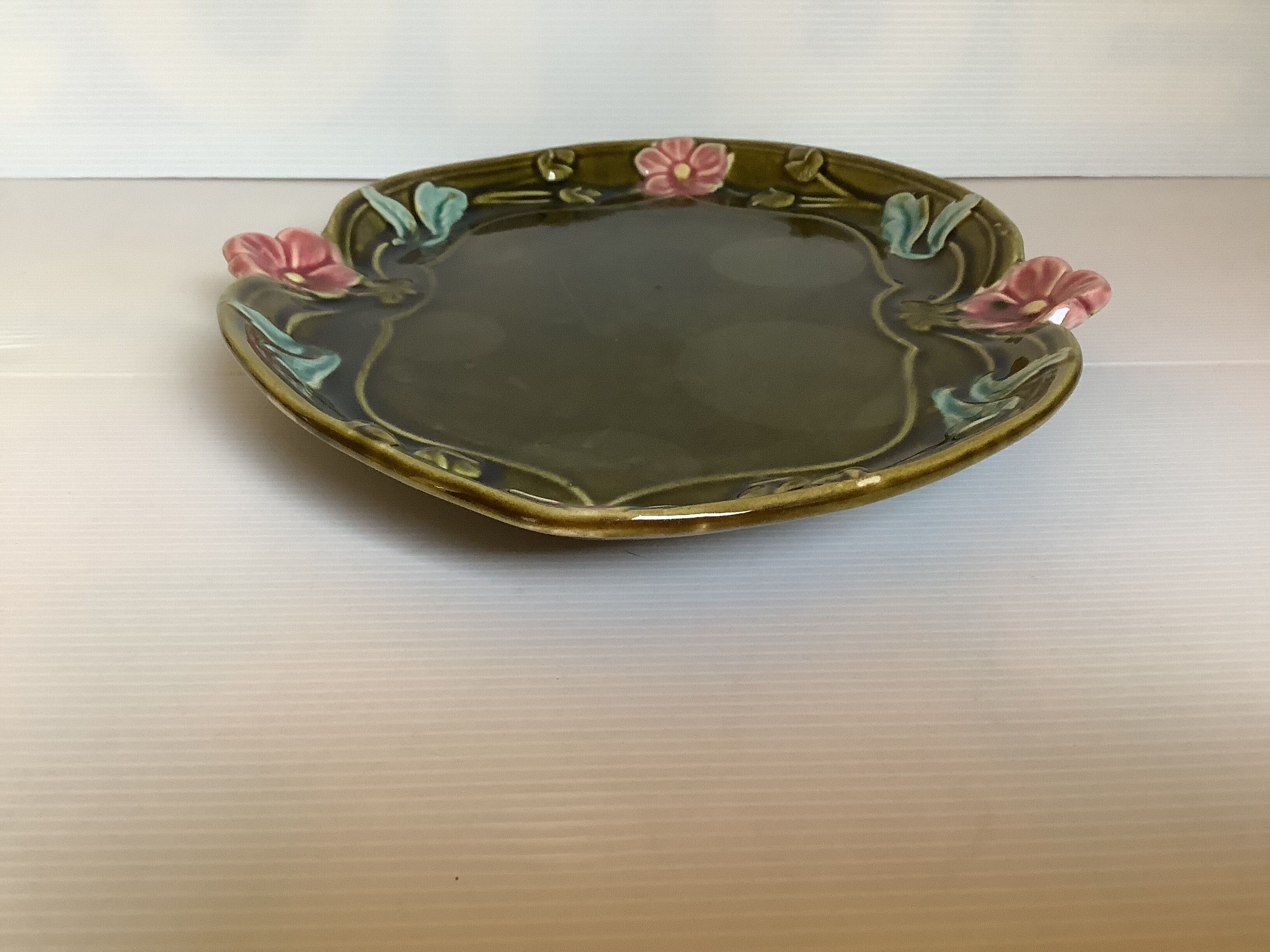 Old khaki green earthenware dish and pink flowers