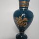Small turquoise blue and gold porcelain vase with elegant floral patterns.