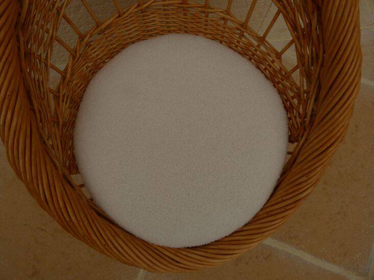Wicker armchair with a high back and its boucle fabric cushion.