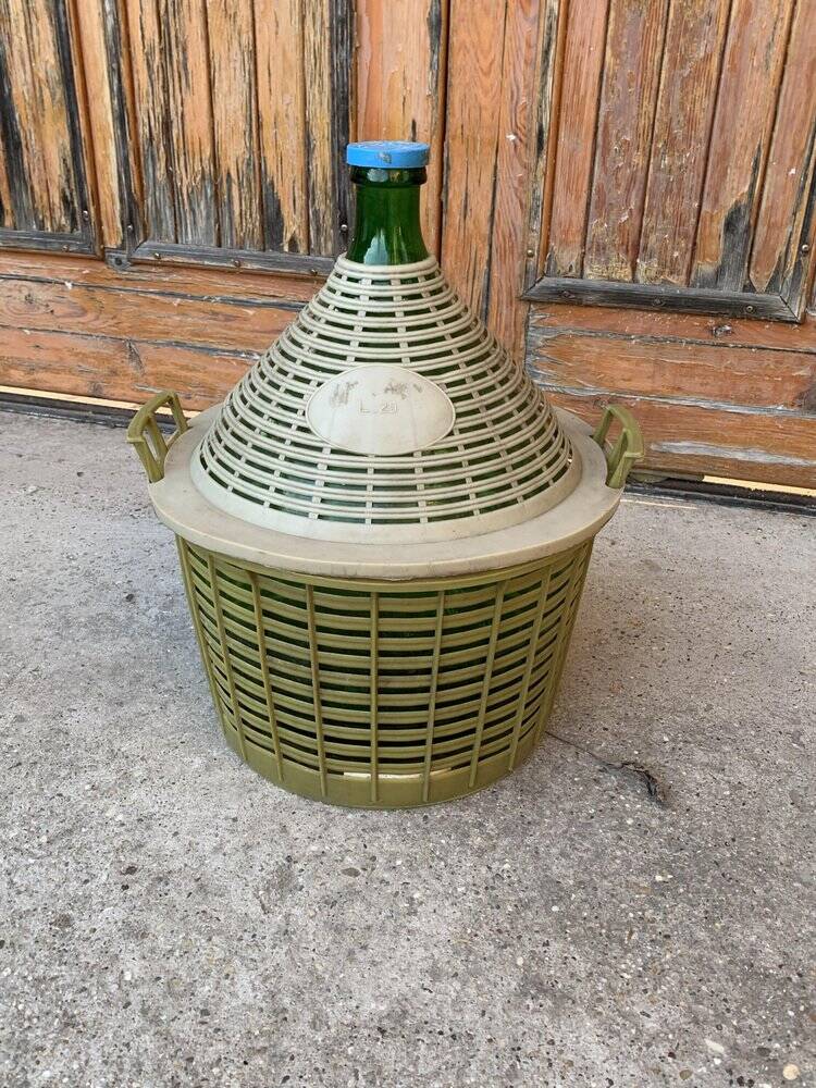 Large green glass lady-Jeanne in a khaki plastic basket, mid-century style.