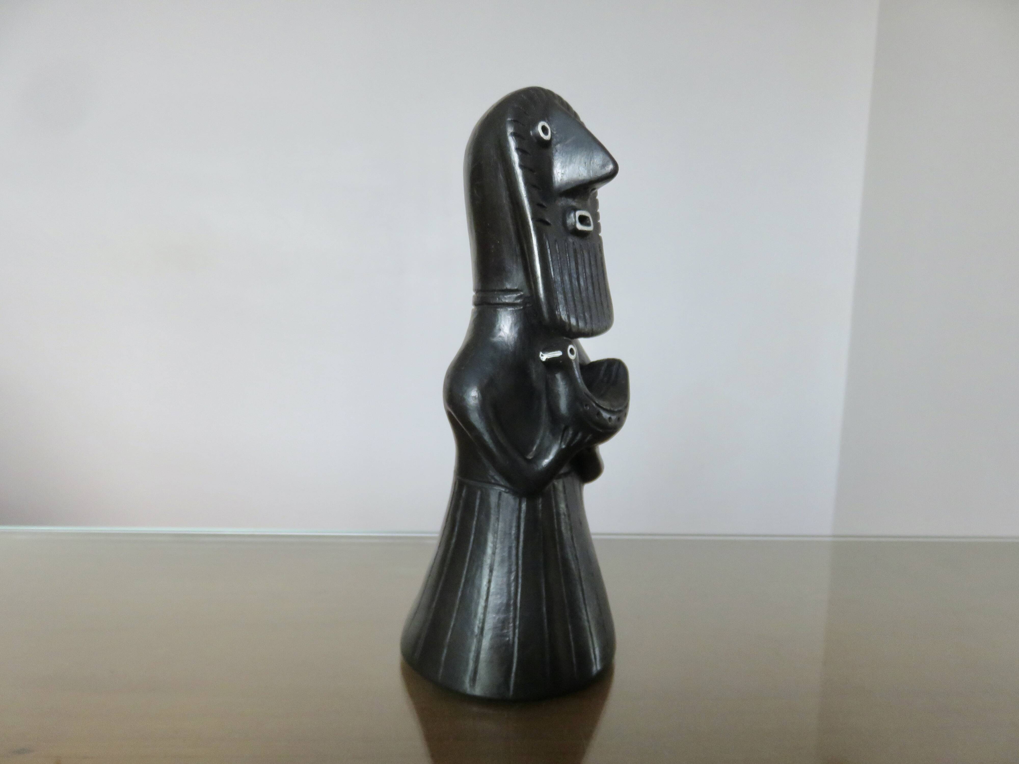 Matte black ceramic sculpture representing a female tribal figure.