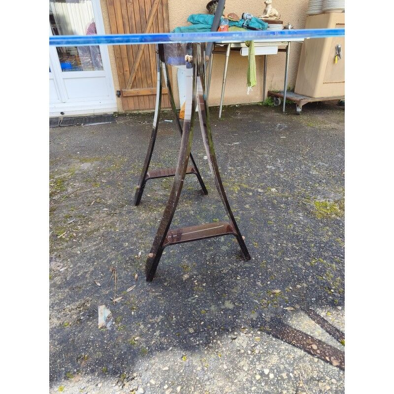 Vintage table with a glass top and smoked plastic trestle legs.