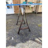 Vintage table with a glass top and smoked plastic trestle legs.