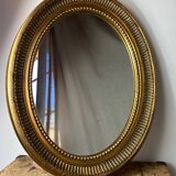 Oval-shaped wooden mirror in gold color