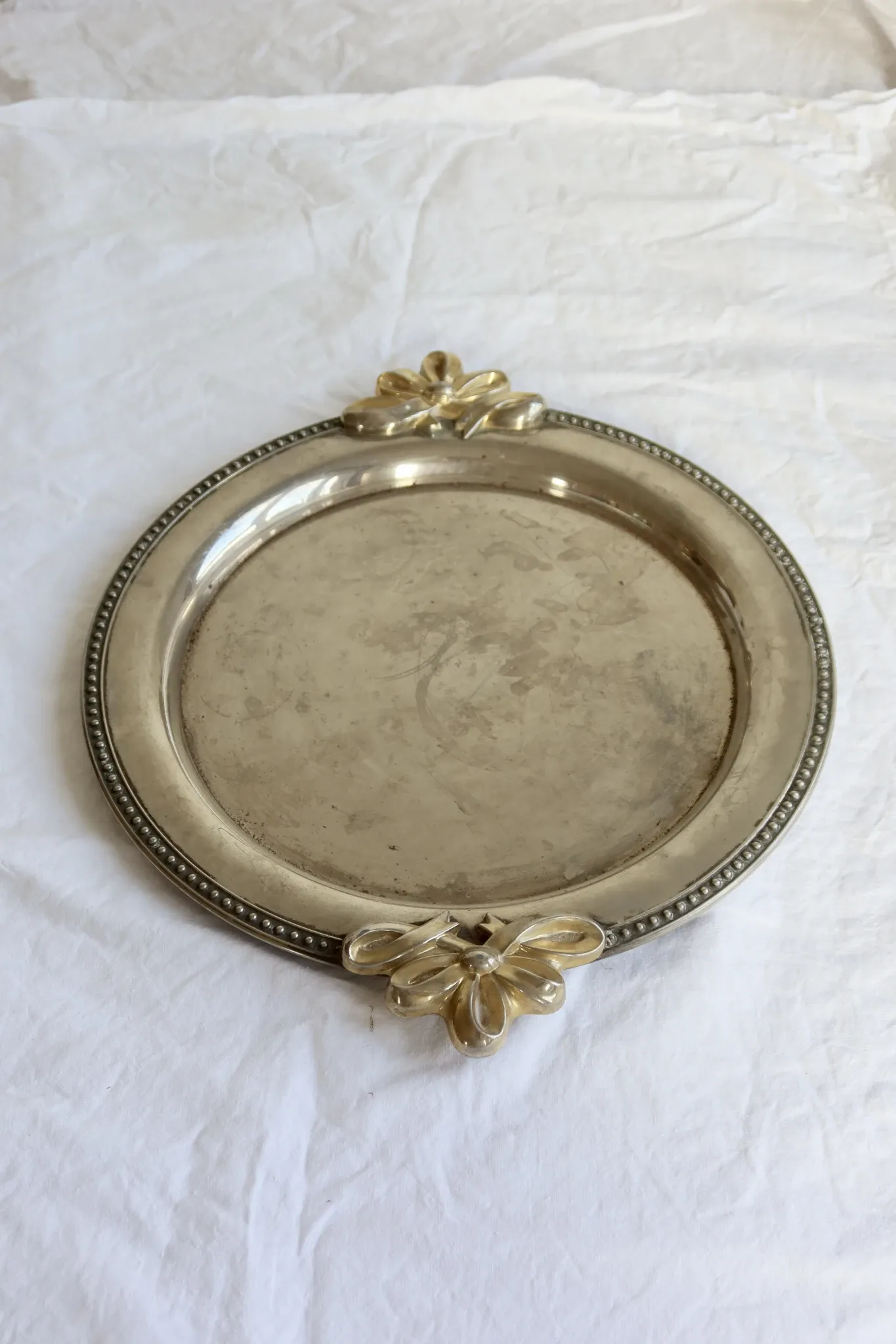 Vintage silver-plated serving tray with bow handles.