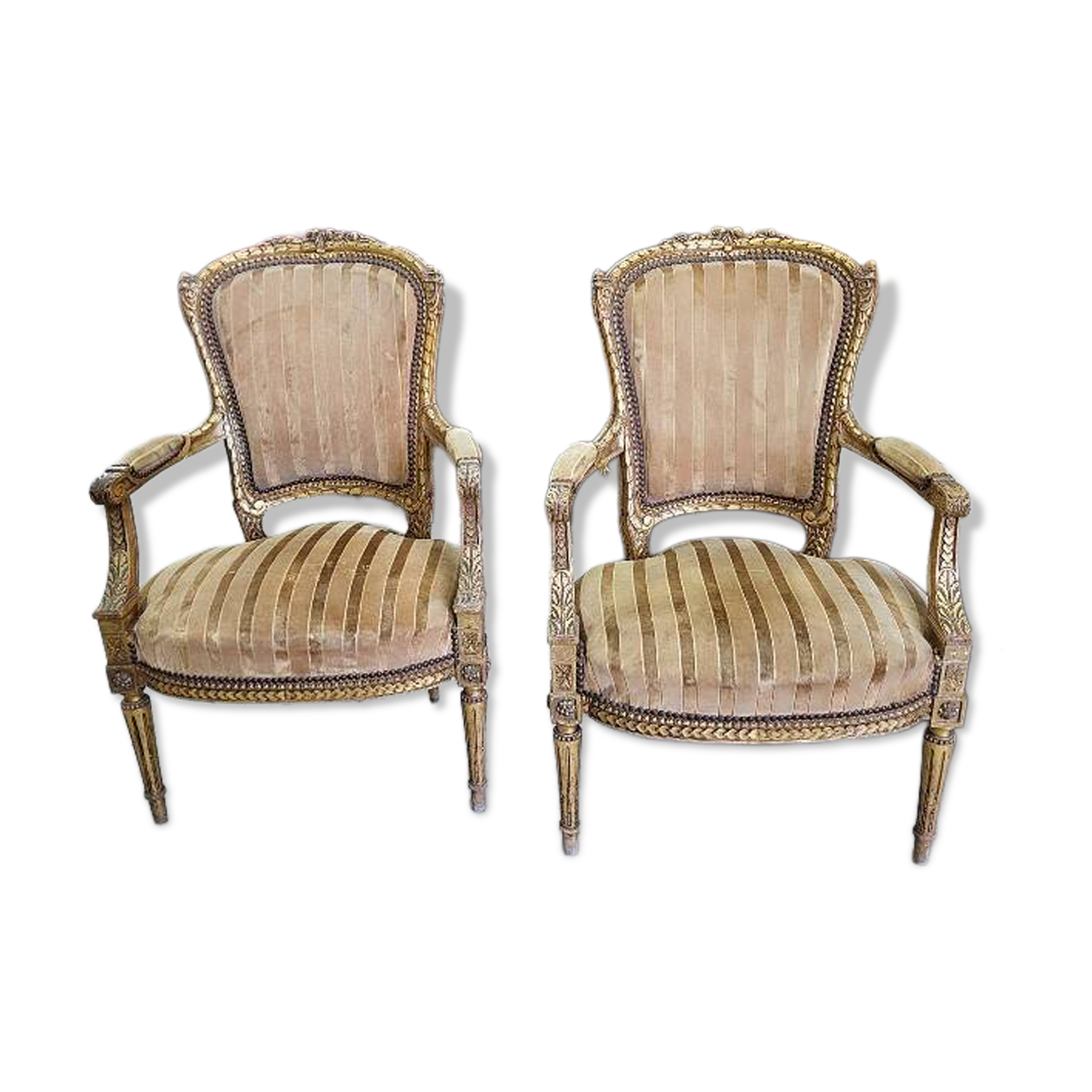 A pair of gilded wooden armchairs in the Louis XVI style.
