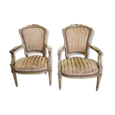 A pair of gilded wooden armchairs in the Louis XVI style.