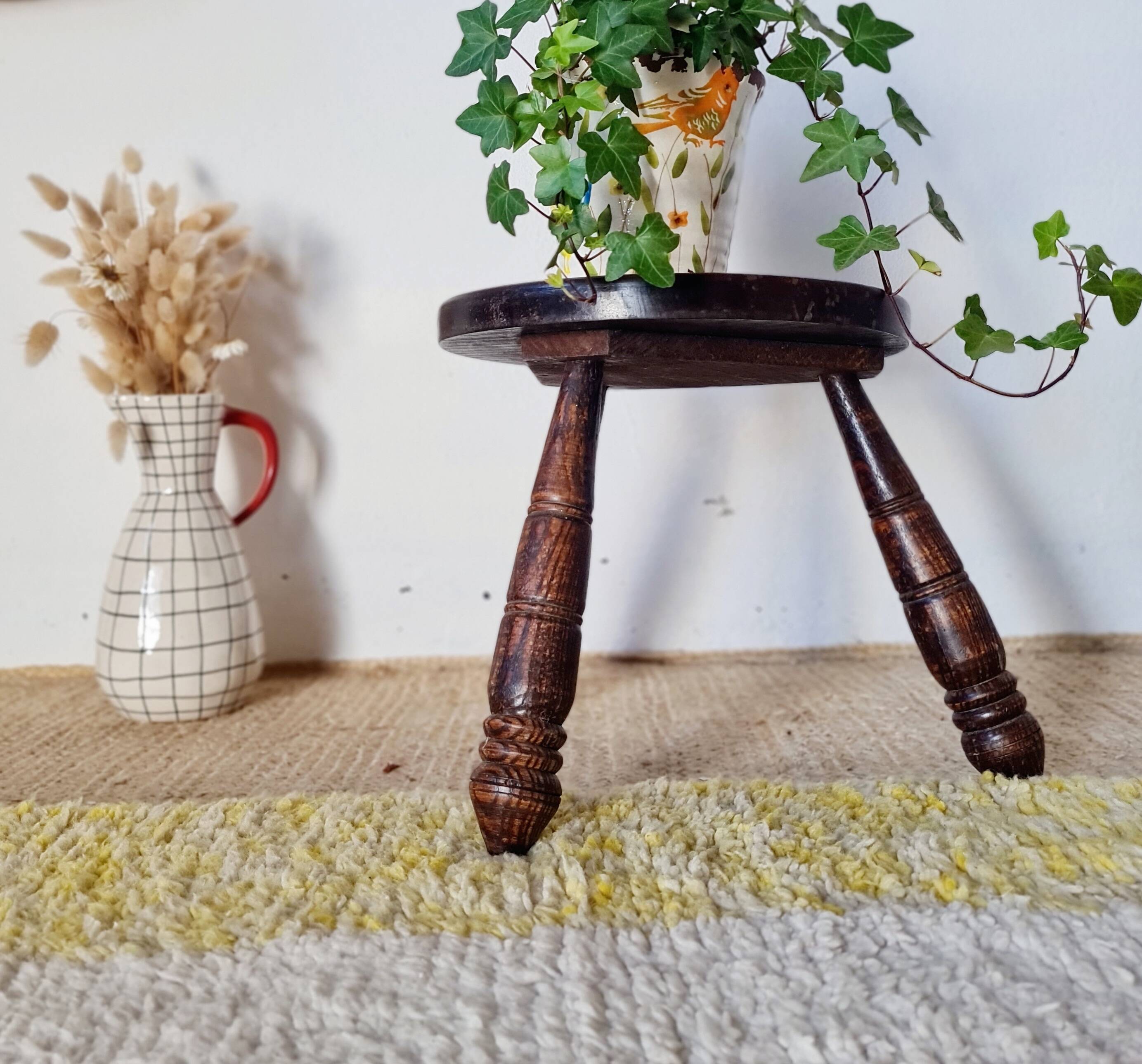 Small brutalist tripod stool made of turned wood.