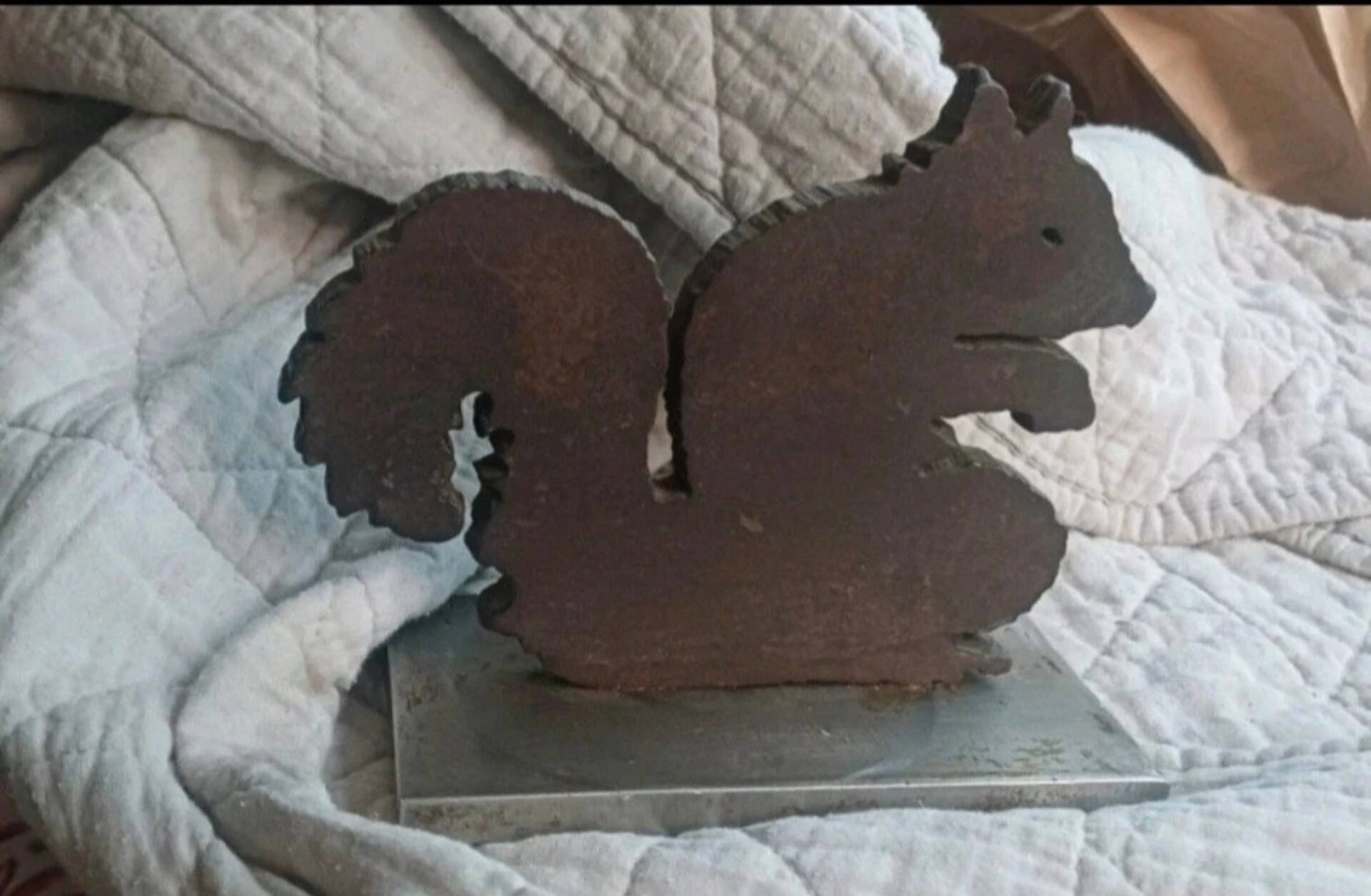 Squirrel bookends in rusty metal on a steel base.