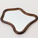 Antique wall mirror in carved wood with a wavy shape and a golden trim.