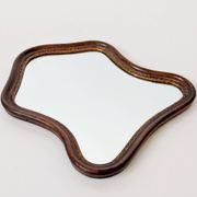 Antique wall mirror in carved wood with a wavy shape and a golden trim.