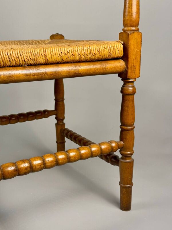 Chaise d'angle vintage en bois avec assise en paille tissée.