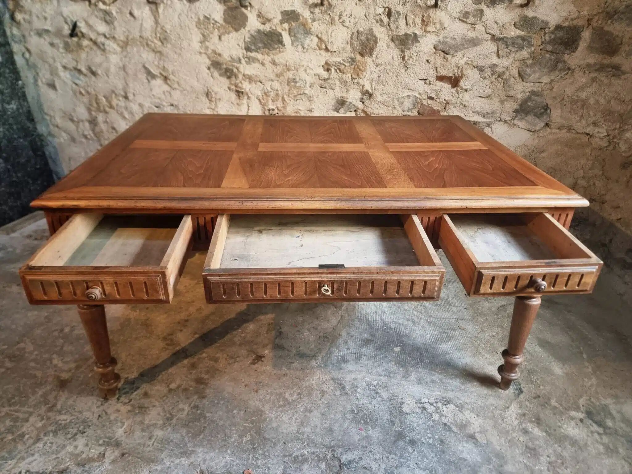 Antique French walnut table with six drawers, parquet top, early 20th century.