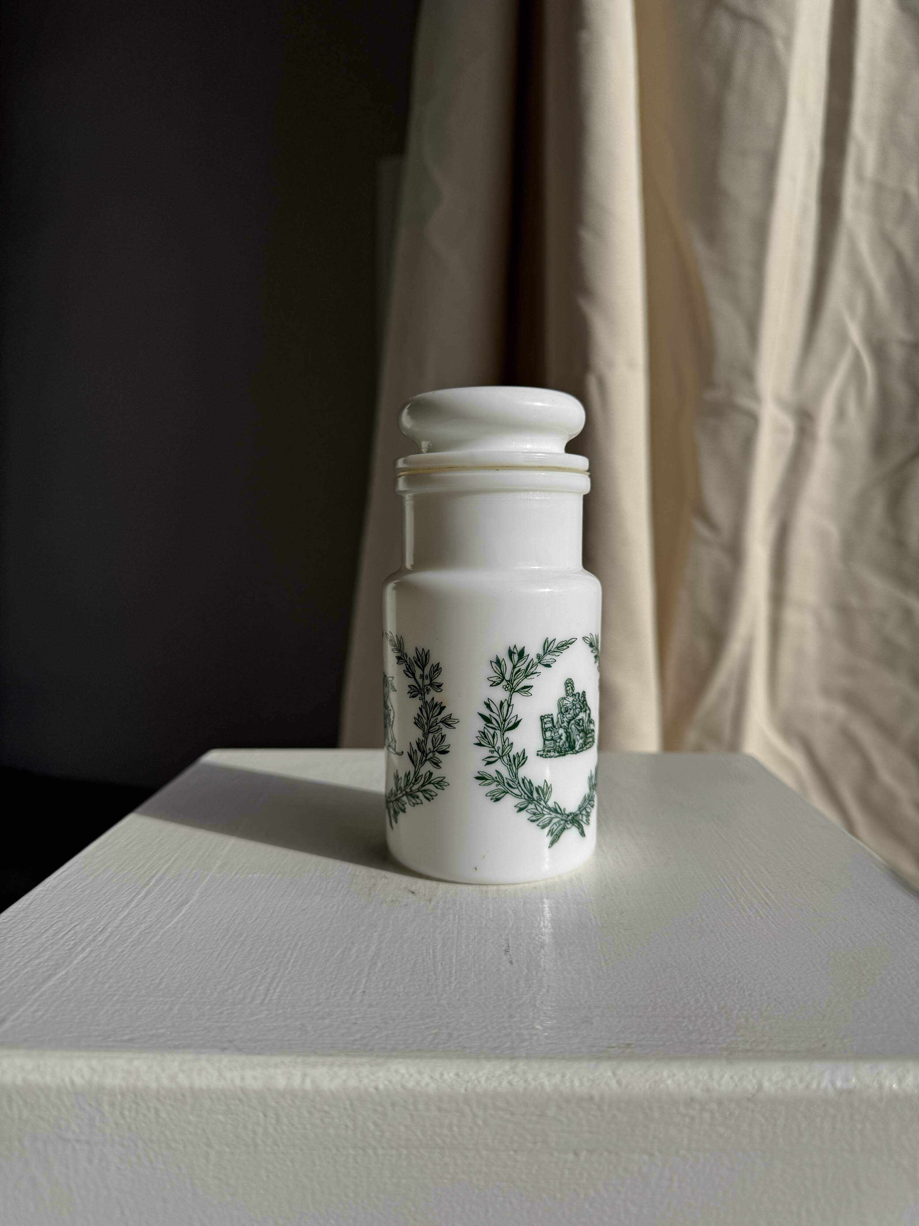 A pair of white glass bottles with Italian green patterns.