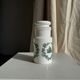 A pair of white glass bottles with Italian green patterns.