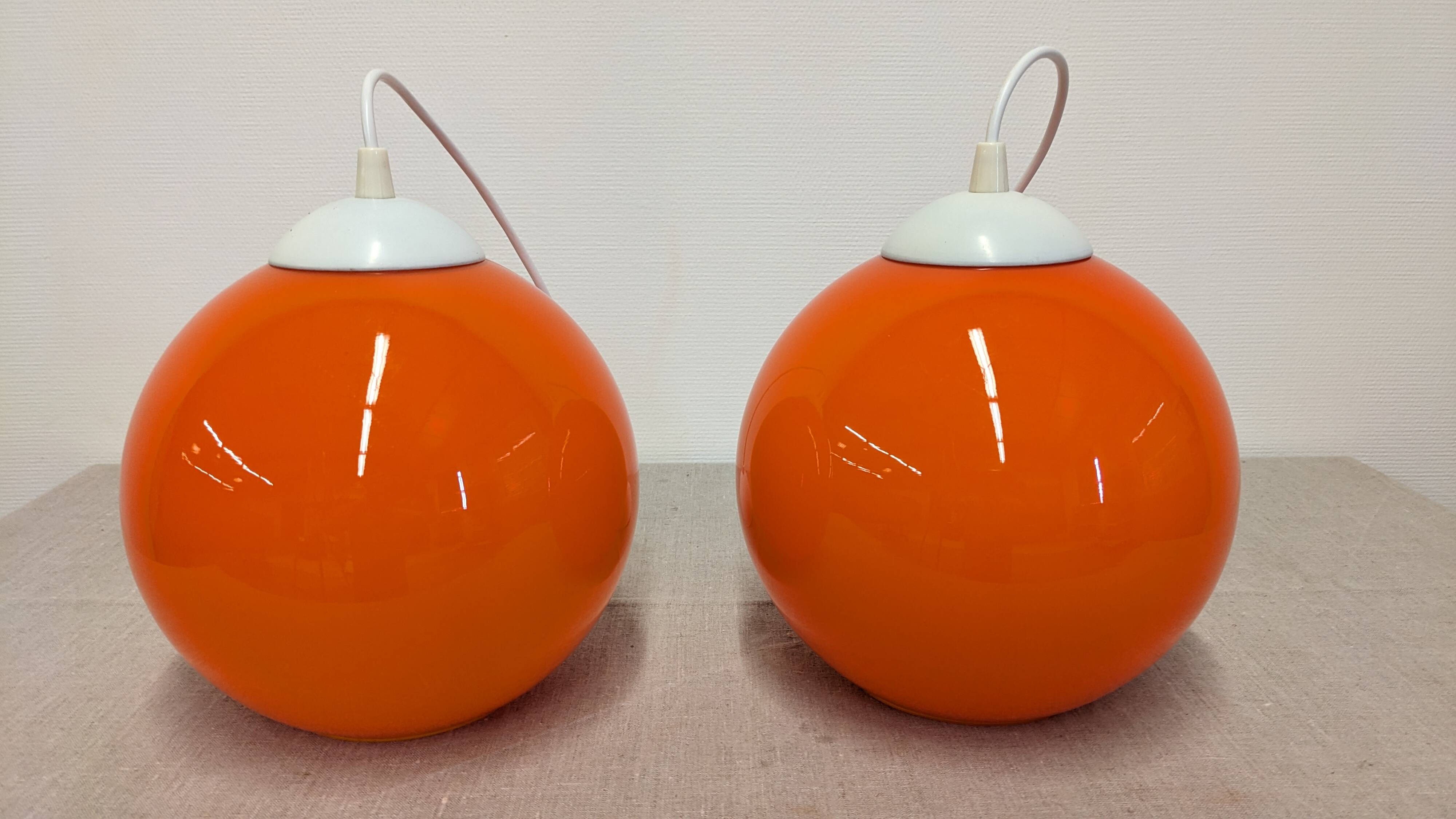 Pair of spherical pendant lights in orange opaline, France circa 1970.