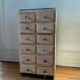 Vintage antique workshop cabinet with 12 drawers in raw wood.