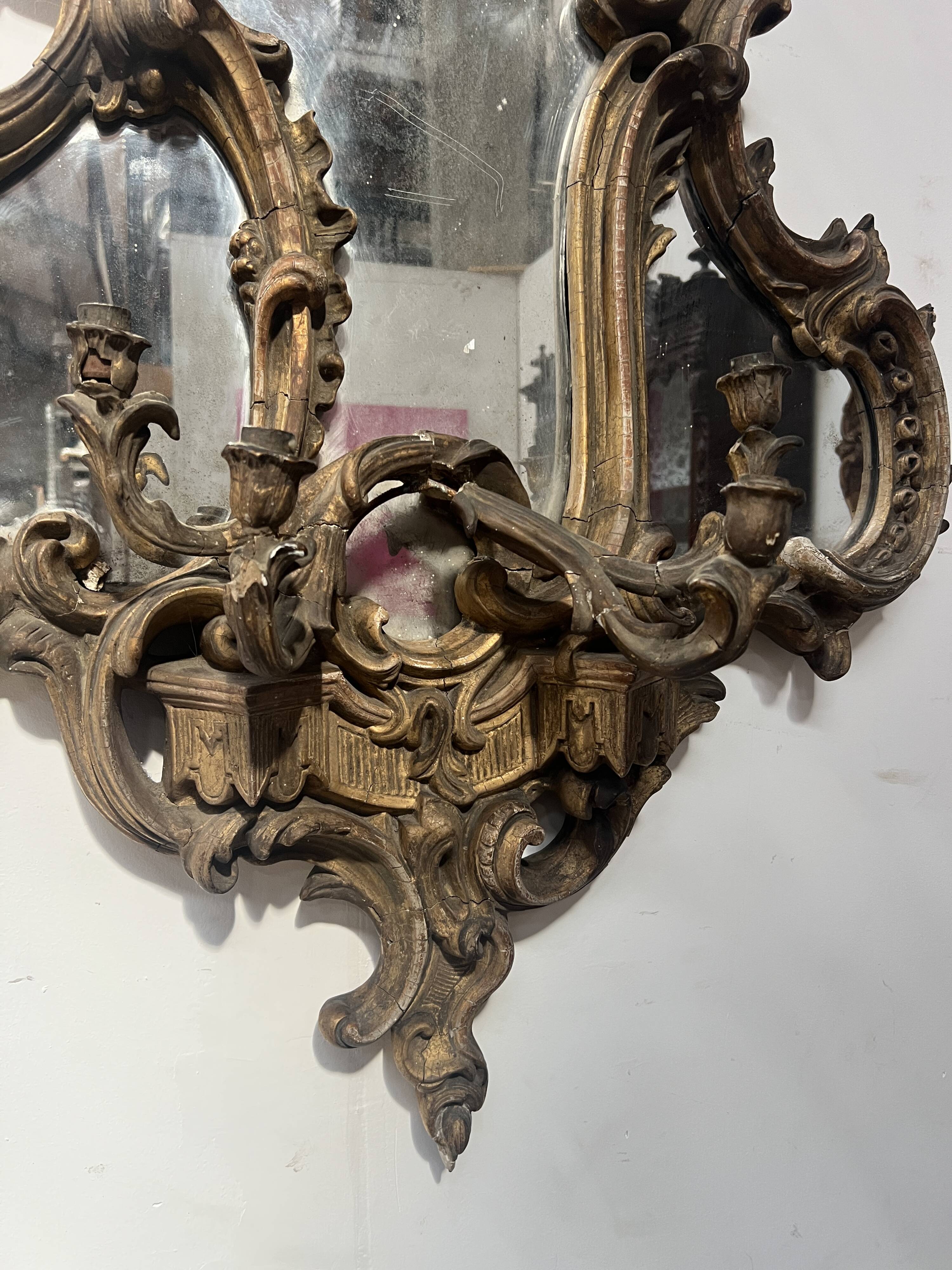 Mirror with a decorative frame featuring a four-light wall sconce, 19th century.