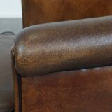 Fauteuil club en cuir de mouton foncé avec passepoil noir