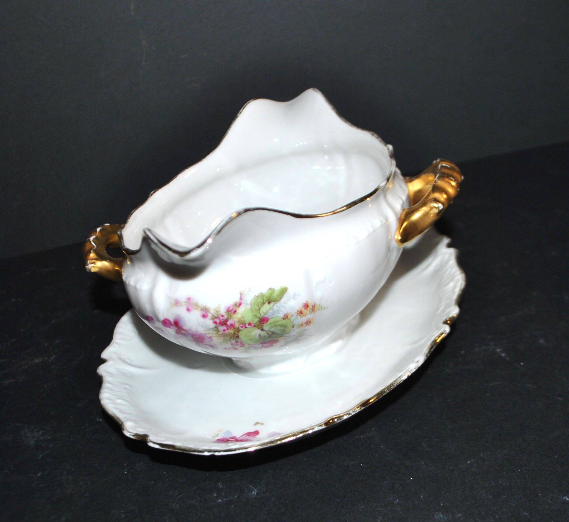 Vintage pouring sauce boat in floral porcelain with gilding.