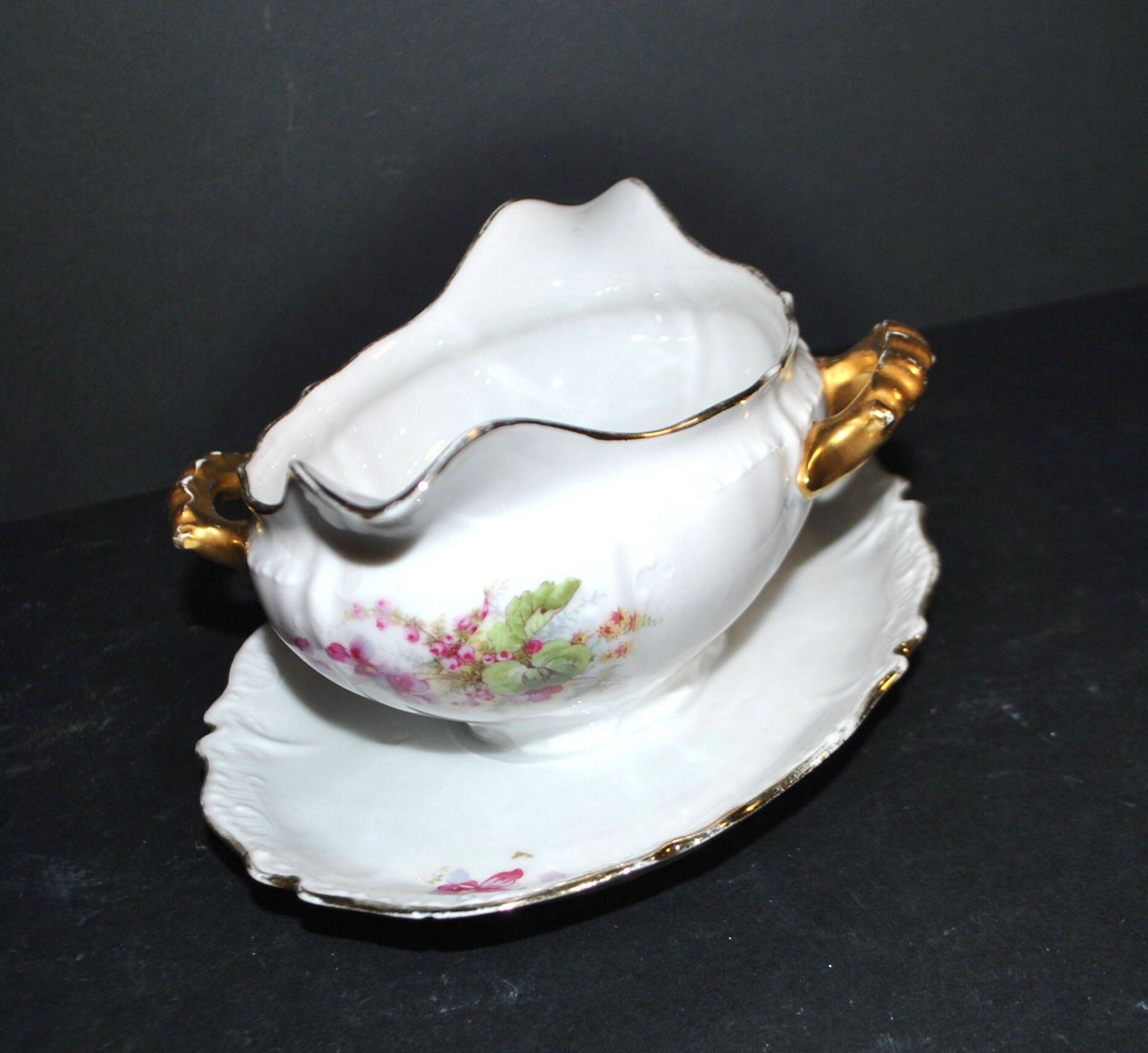 Vintage pouring sauce boat in floral porcelain with gilding.