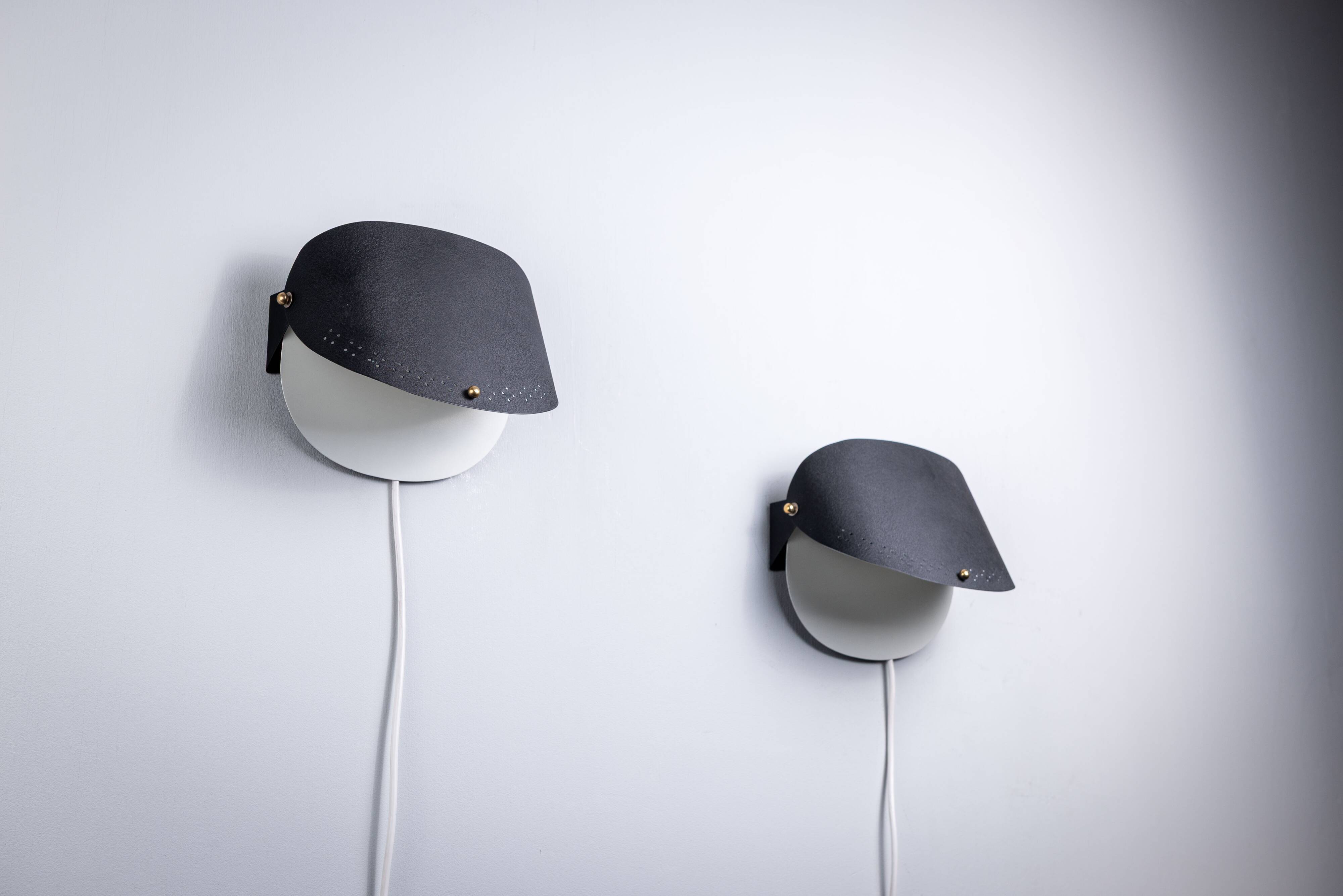 Matte black wall lamps with perforated shades and brass details