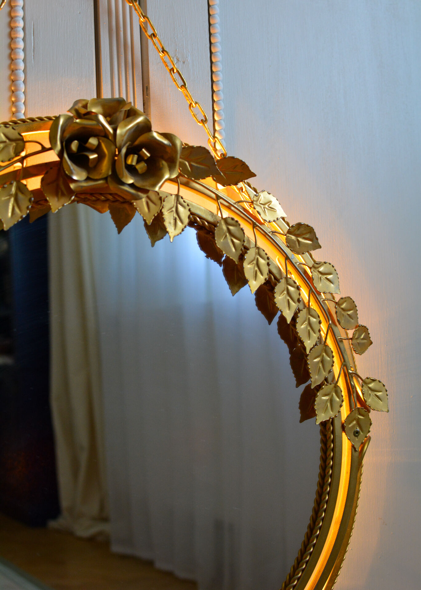 Vintage round illuminated mirror in gold metal with rose decoration.