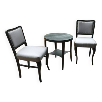 Art Deco set from the 1920s – 2 black chairs and a round brown wooden table with fabric.