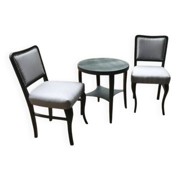 Art Deco set from the 1920s – 2 black chairs and a round brown wooden table with fabric.