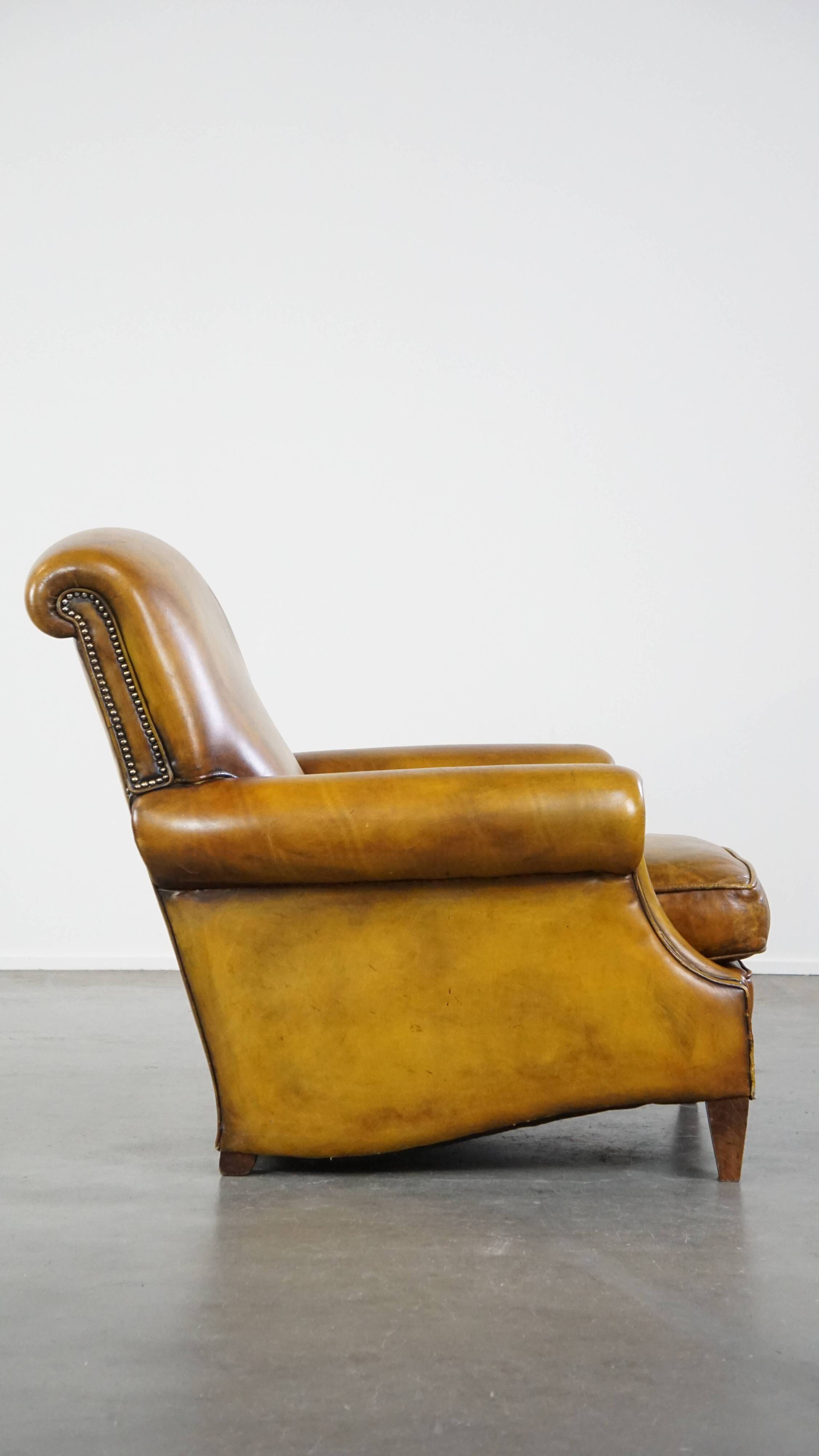 Comfortable large yellow English-style leather armchair with a fine finish and decorative nails