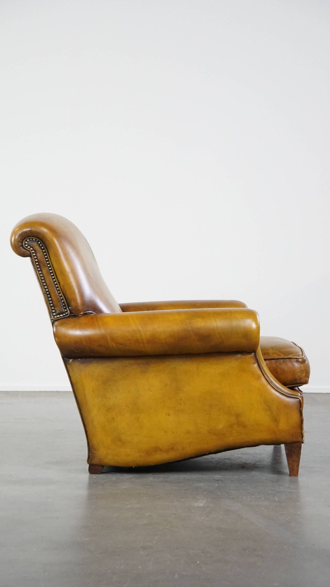Comfortable large yellow English-style leather armchair with a fine finish and decorative nails