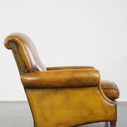 Comfortable large yellow English-style leather armchair with a fine finish and decorative nails
