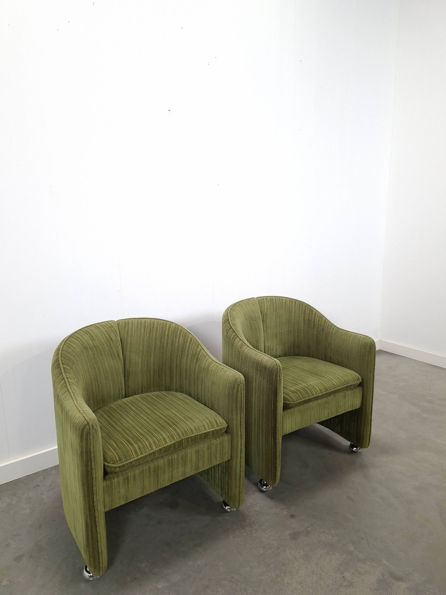 Chaises de cocktail vertes avec des roues chromées.
